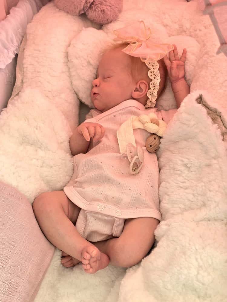 Slapend pasgeboren baby'tje in roze omgeving